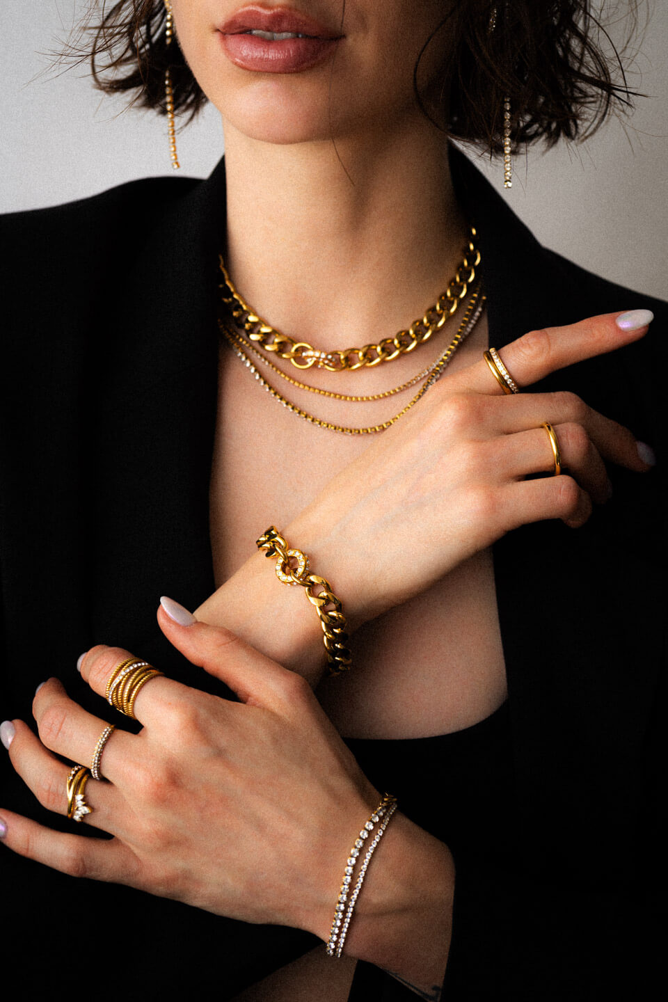 Model mit schwarzem Outfit und viel goldenen Schmuck mit Zirkonia Steinen