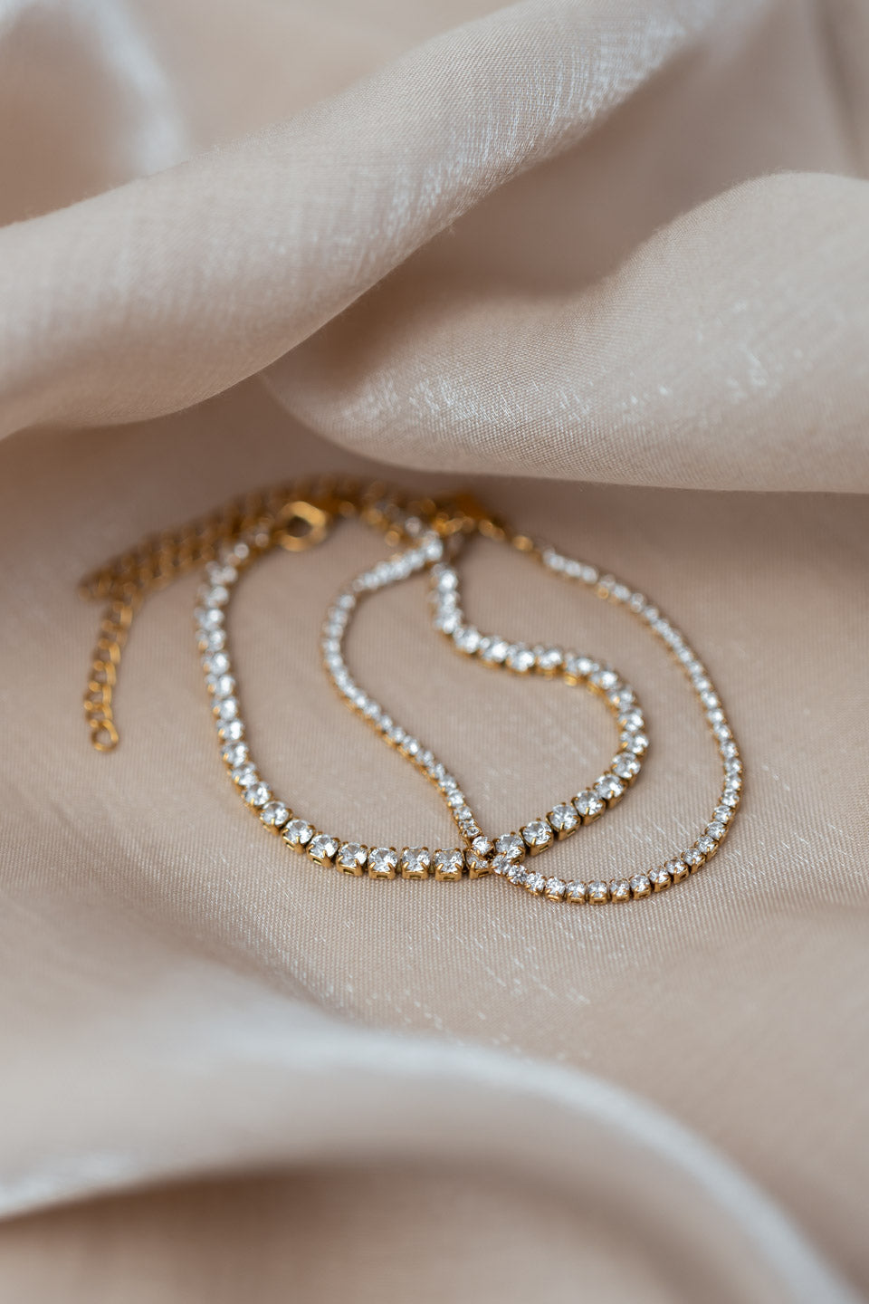 Zwei goldene Armbänder, die mit Zirkonia Steinen besetzt sind