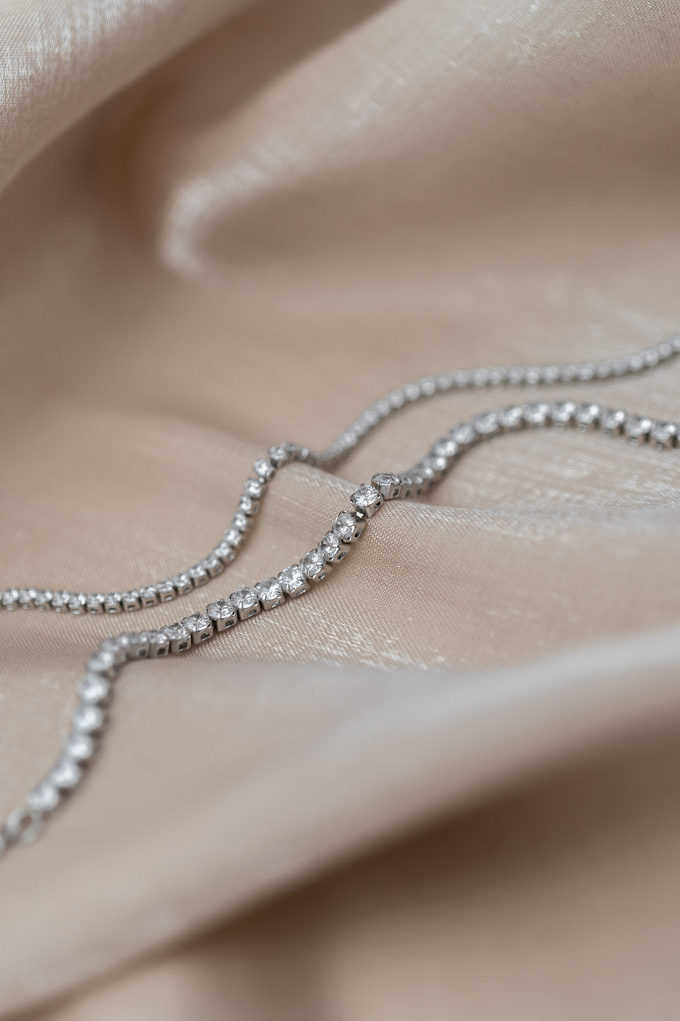 Detailaufnahme von zwei silbernen, mit Zirkoniasteinen besetzten Armbändern