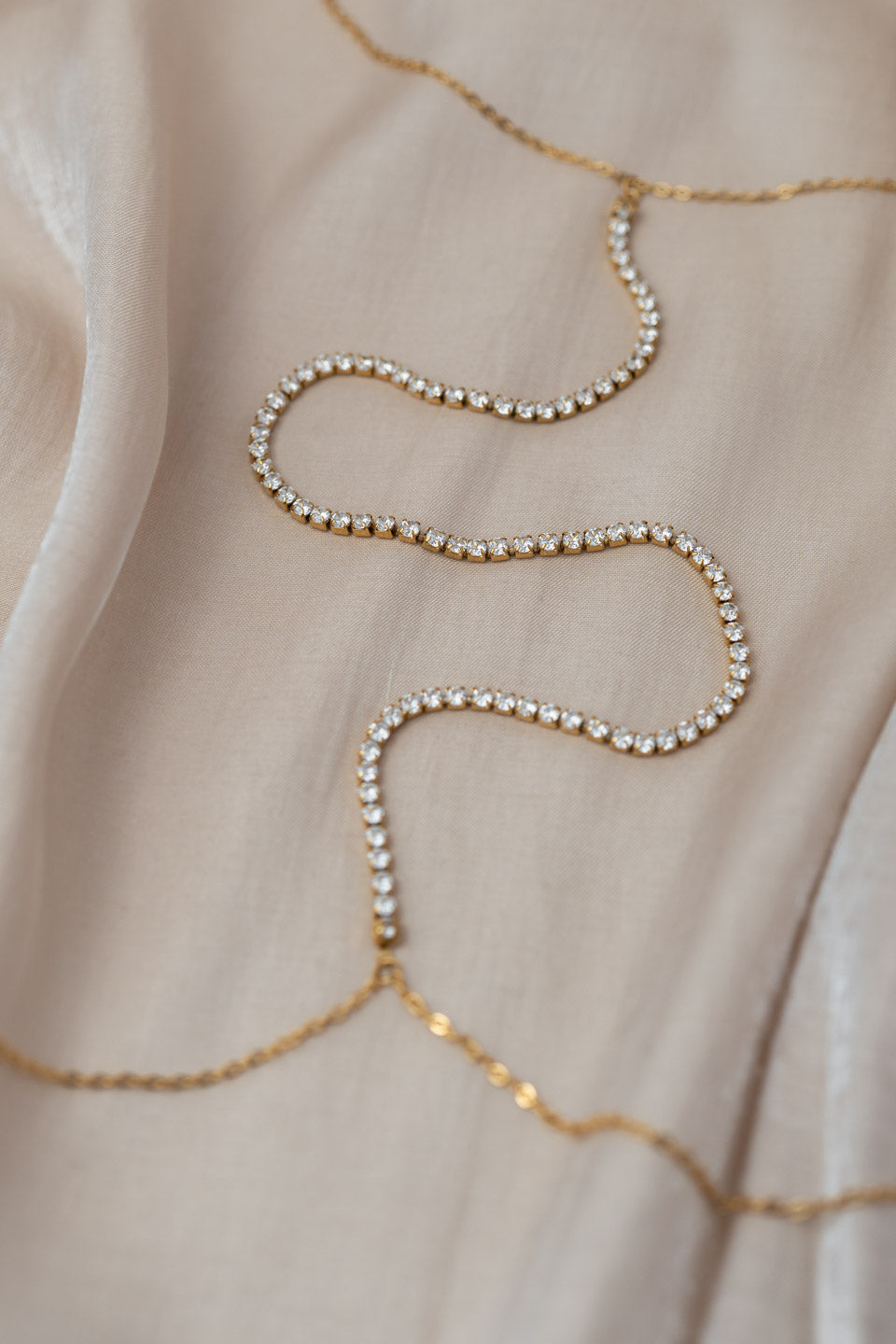 Detailaufnahme einer goldenen Körperkette mit Zirkonia Steinen