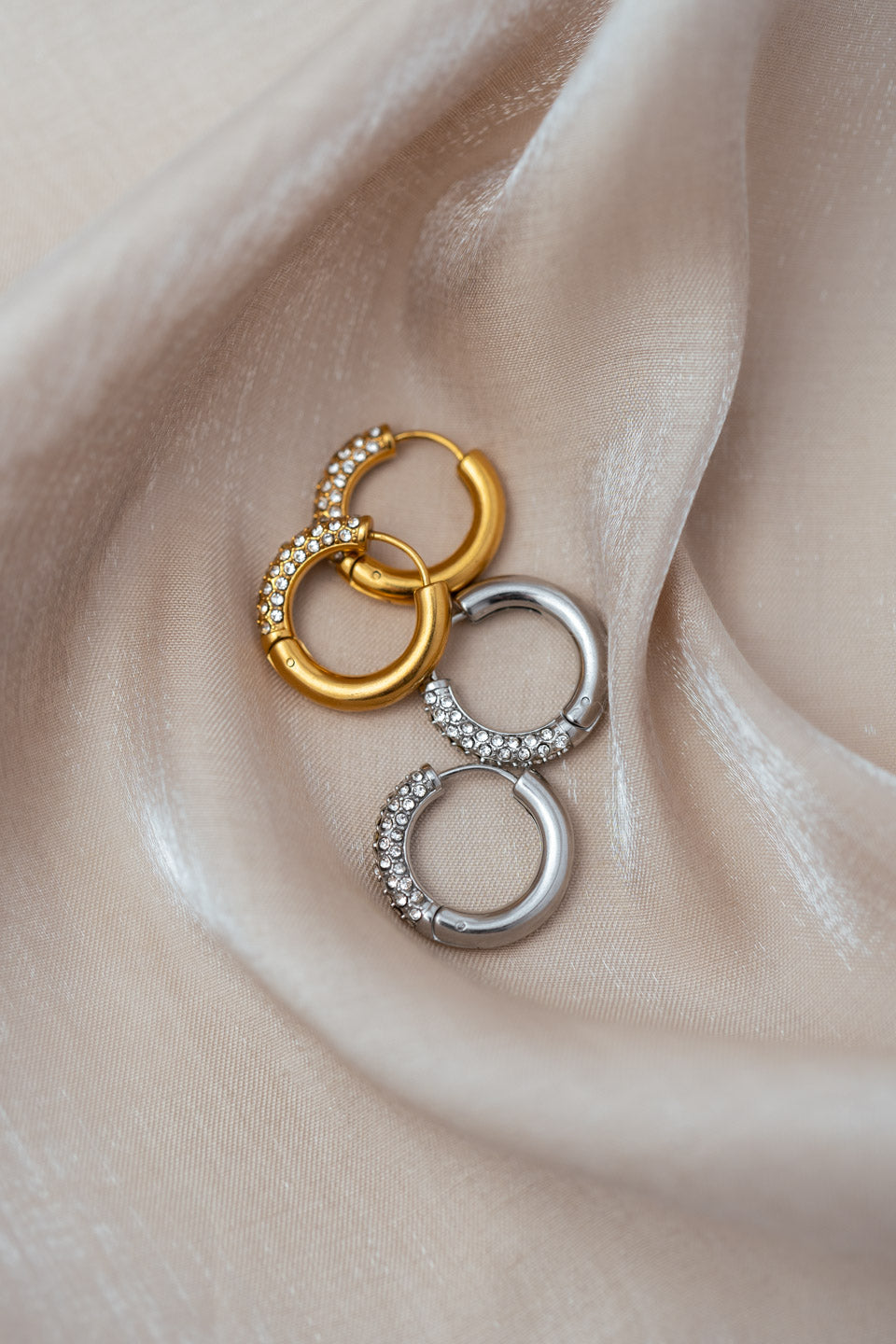 Breite Creolen in Gold und Silber, die zur Hälfe mit vielen kleinen Zirkonia Steinen besetzt sind
