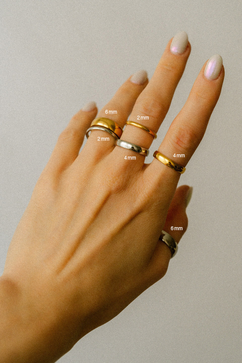 Unterschiedlich breite Ringe in Gold und Silber an einer Frauenhand