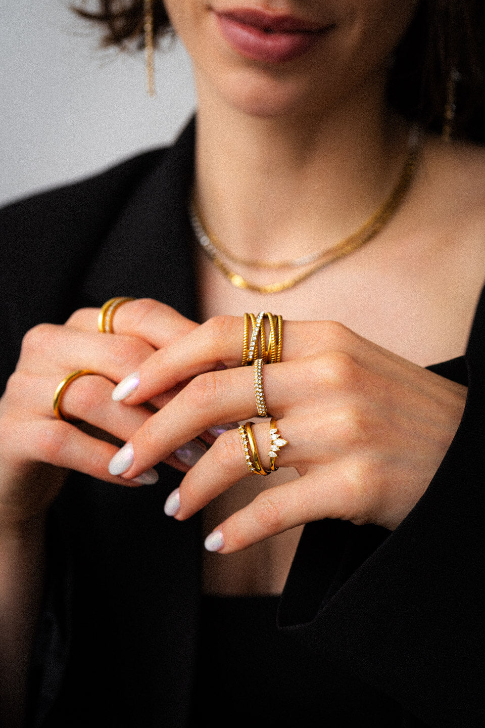 Nahaufnahme von zwei Frauenhänden, die viele, goldene Ringe mit Zirkonia Steinen tragen