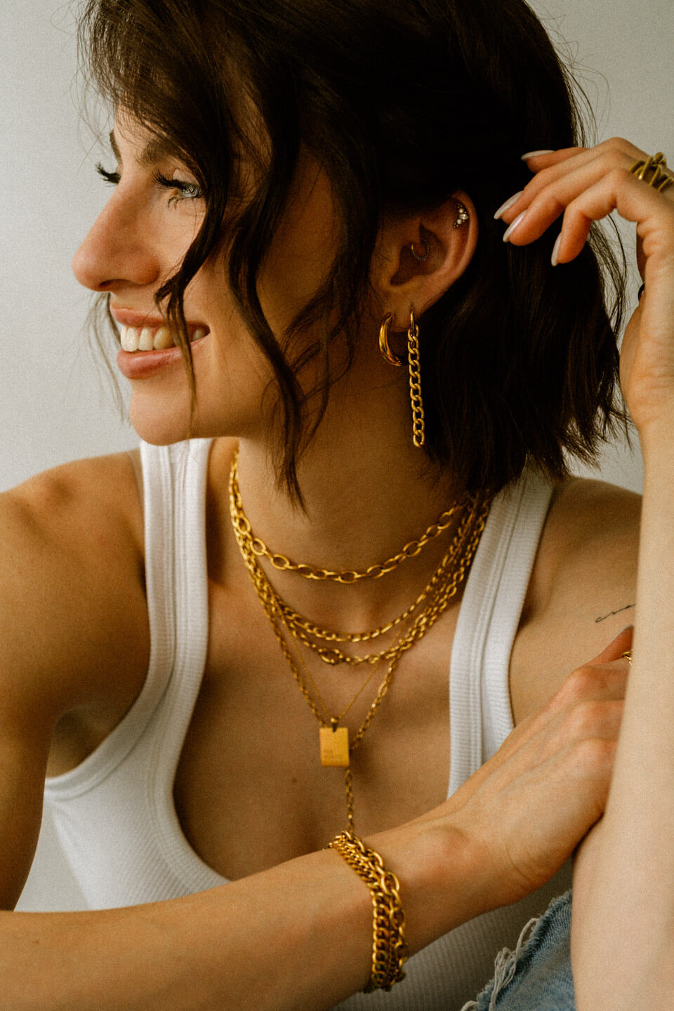 Frau mit auffälligen Ohrringen, vielen Halsketten und Armbändern in Gold