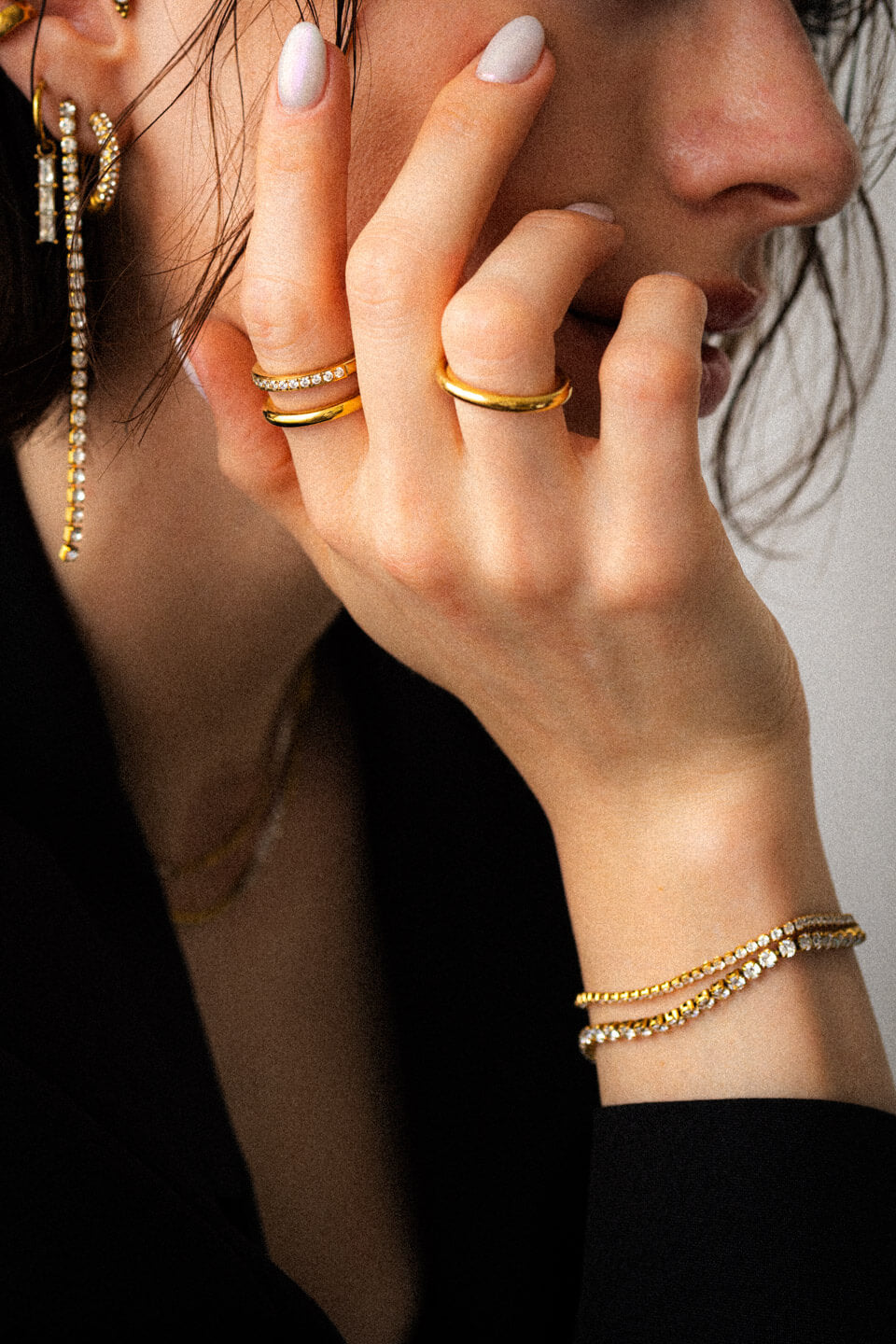 Detailaufnahme einer Frau, die viel Goldschmuck wie Ringe, Armbänder und Ohrringe trägt