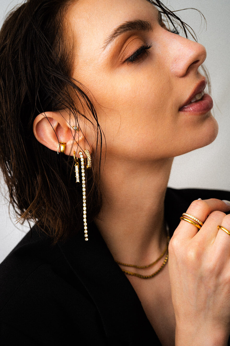 Portrait einer jungen Frau mit vielen, sehr auffälligen goldenen Ohrringen mit glitzernden Zirkonia Ohrhängern